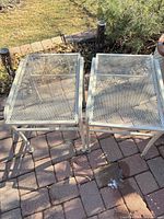 Two matching metal mesh-top square tables