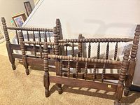 Headboard and footboard leaning against wall showing turned spindles and posts