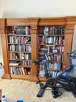 Front view of two-section carved oak bookcase fully loaded with books