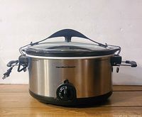 Front view of Hamilton Beach slow cooker showing stainless body, glass lid and locking handles
