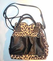 Front view showing leopard body, two black faux-leather front pockets, top handles and shoulder strap