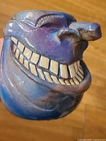 Front view of blue-purple ceramic mug showing grinning face and teeth