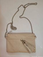 Front view of beige faux leather purse with chain strap and tassel