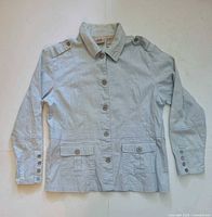 Front view of light blue Bill Blass women’s jacket showing button front, epaulets, pockets, cuffs