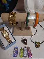 Overview of bangles on stand, watch in box, six glass pendants
