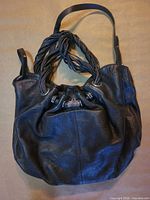 Full view of dark brown pebbled leather purse front and handles