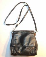 Front view of black leather crossbody purse showing flap and strap