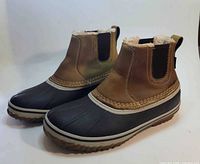 Side view of both boots showing leather upper, rubber shell and sherpa lining