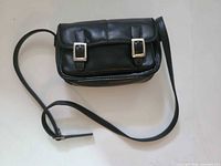 Front view of black leather bag with buckle accents and strap