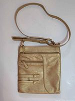 Front view of gold leather crossbody bag with adjustable strap and front zipper compartment