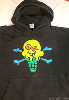 Front view of black hoodie with ice-cream graphic and pouch pocket