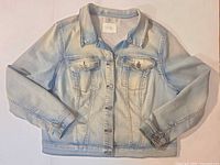 Front view of light wash denim jacket showing button front and chest pockets