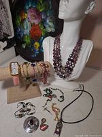 Lot overview showing watch, bracelets, Czech glass necklace on bust, rosary, pendant necklace and brooches