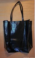Front view of black faux leather tote showing shine, straps, snap detail