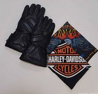 Top view of black leather gauntlet motorcycle gloves and folded Harley-Davidson flame bandana