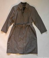 Front view of grey plaid trench coat with belt displayed flat