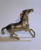 Left profile of silvertone metal horse figurine standing on two legs