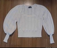 Front view of white Mink Pink knit sweater laid flat