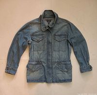 Full view front of light blue denim jacket laid flat