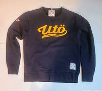 Front view of navy sweatshirt with yellow Utö applique and bottom hem patch visible