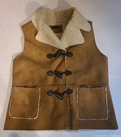 Front view of tan faux suede vest with toggle closures and pockets