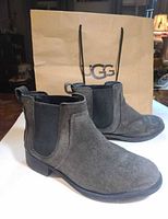 Three-quarter view of both boots with UGG shopping bag