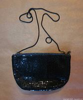 Front view of black metal mesh purse with cord strap shown fully extended