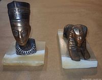 Bust and sphinx figurines side by side on onyx bases