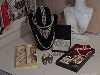 Overall view of multiple jewelry pieces including necklaces on bust, boxed pearls, earrings