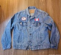 Front view of Levi's denim jacket showing chest pockets, round patch, Canadian flag patch, lapel pins