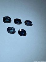 Five oval cut blue sapphires on white background