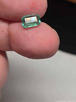 Close-up of rectangular octagon emerald held between fingers