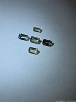 Five rectangular mint green Tanzanite stones on neutral background