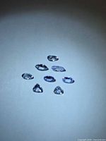 Top view of eight faceted bluish-violet Tanzanite stones on white background