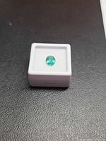 Front view of emerald in box showing color and cut