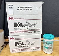 Two shipping boxes labeled NCL disinfectant wipes with one canister displayed