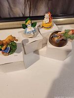 Four boxed Lenox Disney thimbles with character figures displayed on top