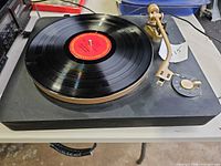 Overall view of turntable with record on platter showing gold rim and tonearm