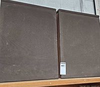 Front view of both Epicure Model 20 speakers with fabric grilles and walnut cabinets