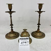Front view of two brass candlesticks and lidded jar