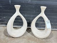 Pair of open-loop off-white textured resin vases front view