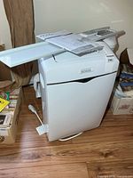 Front view of Noma portable air conditioner with window slider panel, remote and manual on top