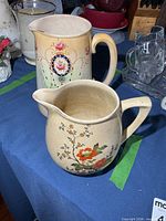 Two pitchers on table, showing relative sizes and decoration