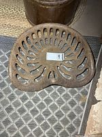 Front view of cast iron tractor seat showing slotted pattern and overall shape