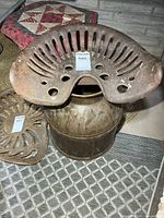 Cast iron tractor seat on top of metal cream can, second seat with different lot number visible