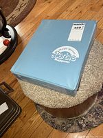 Closed blue Barbie Magic Moves carrying case on stool