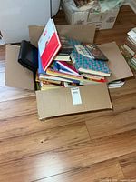 Closed cardboard box open displaying mixed books