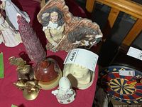 Group shot of ceramic plaque, pottery vase, brass horse, brass bell, candle, porcelain child, ghost holder