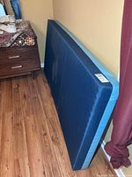 Front side of blue vinyl hospital mattress leaning against wall