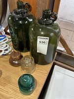 Two green glass jugs and three insulators on tabletop